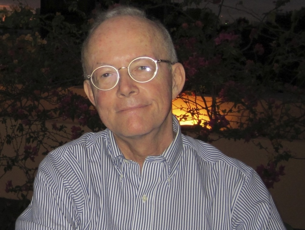 Translator Hoyt Rogers in a striped shirt and round silver glasses.