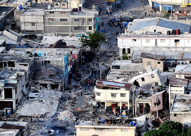 A view from above of dilapidated buildings and rubble on a marketplace street.