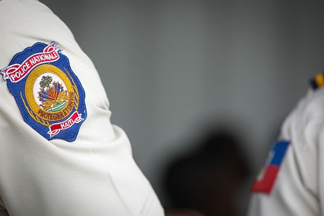 A white shirtsleeve with a blue and gold embroidered patch on the shoulder that reads "Police Nationale Haïti: Protéger et servir."