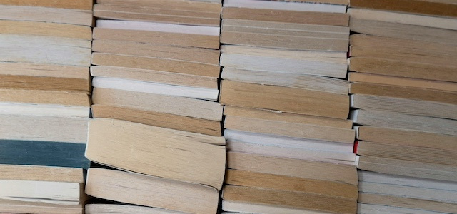 A wall of books on their side, pages facing out.