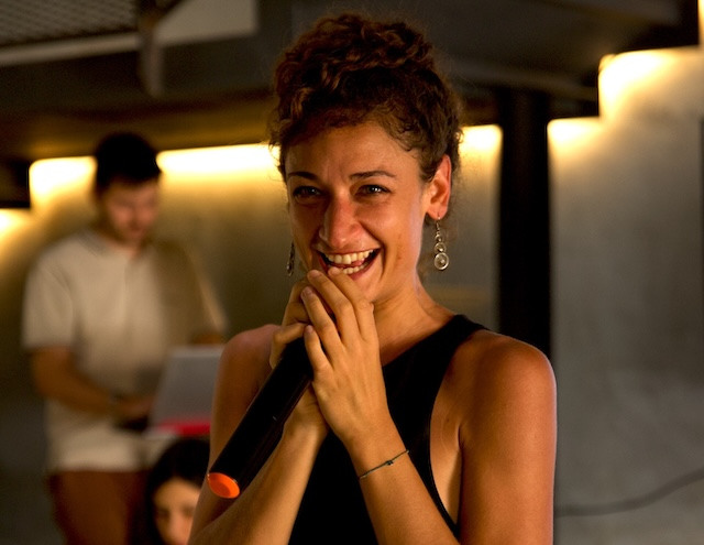 Marie Moïse laughs into a handheld microphone at an event.