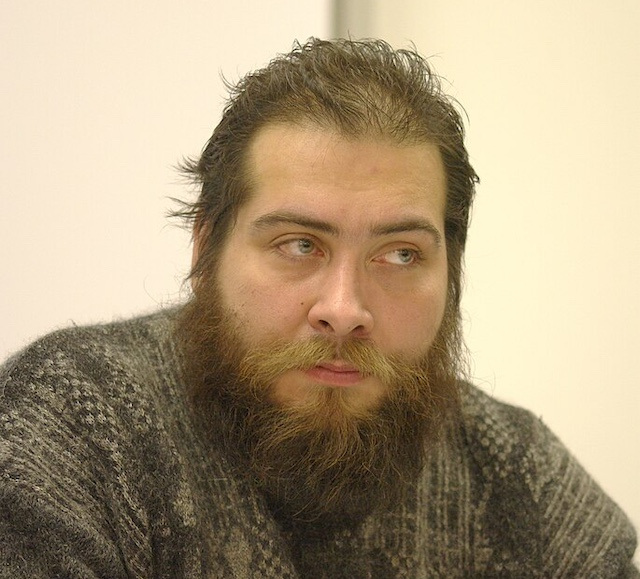 Author Danila Davydov, with brown hair and a beard, wearing a brown sweater. 