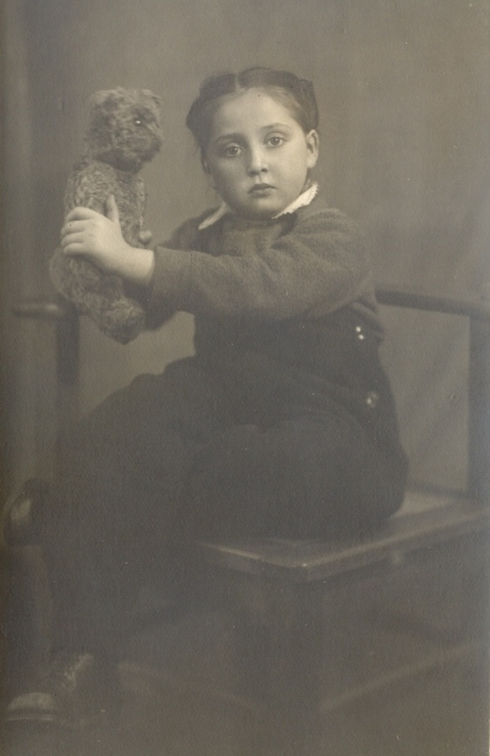 Sepia photograph of a young girl holding a teddy bear.