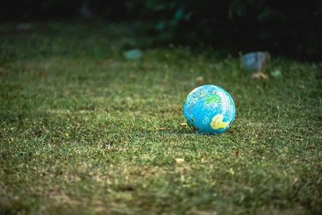 A globe representing the Earth lies on its side on a grass field.