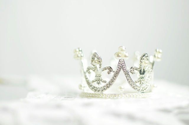 A silver plastic crown with white pearls against a white background.