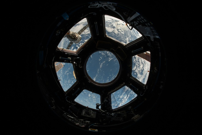 A view of earth from space through the hexagonal windows of a spacecraft's flight deck. 