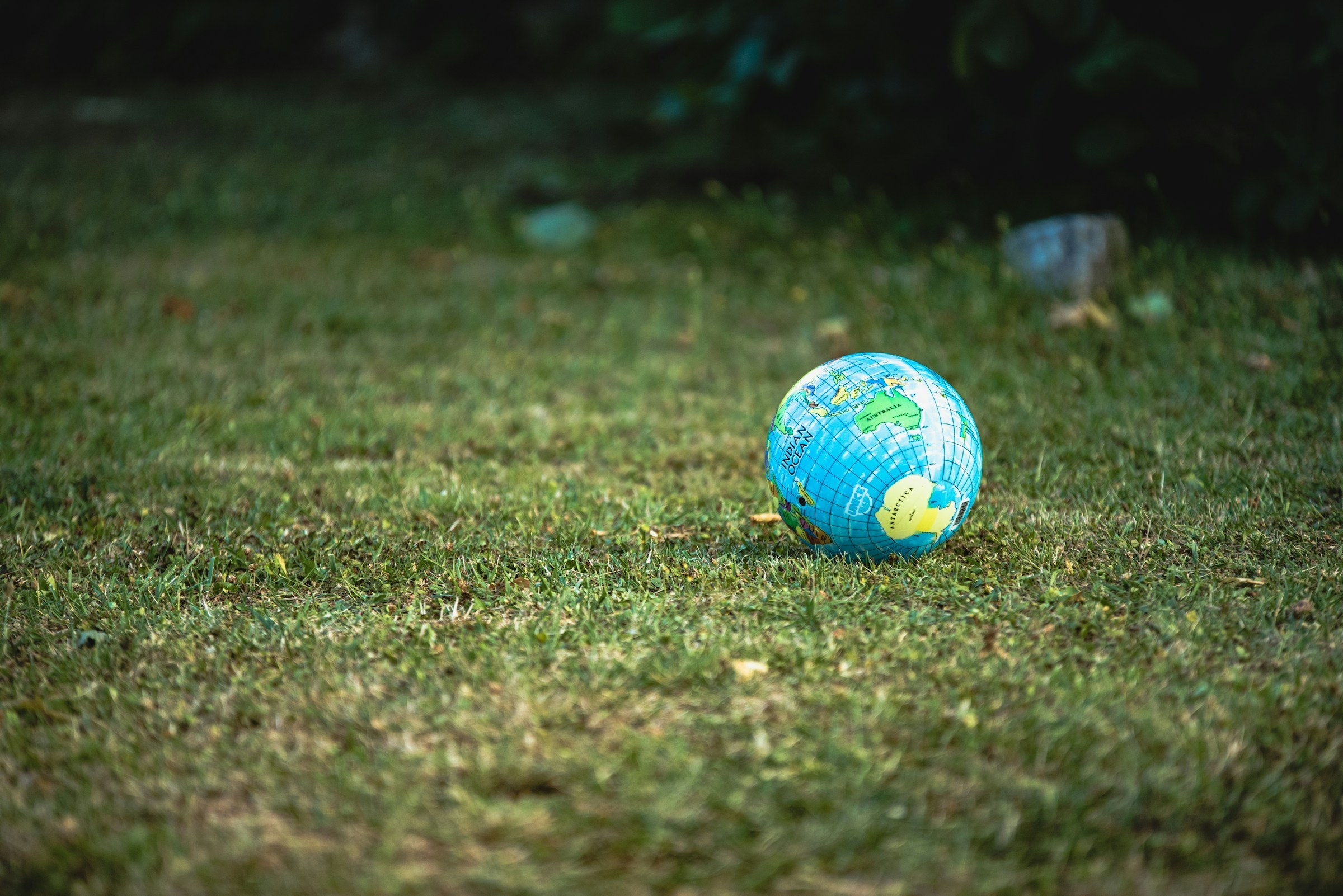 A globe representing the Earth lies on its side on a grass field. 