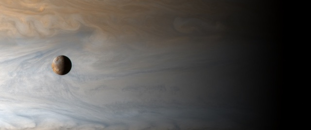 Image of planet jupiter against a background of space, which appears in a blend of blue, gray, and golden colours. 