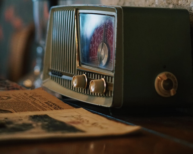 Image of old time radio in front of some magazines.