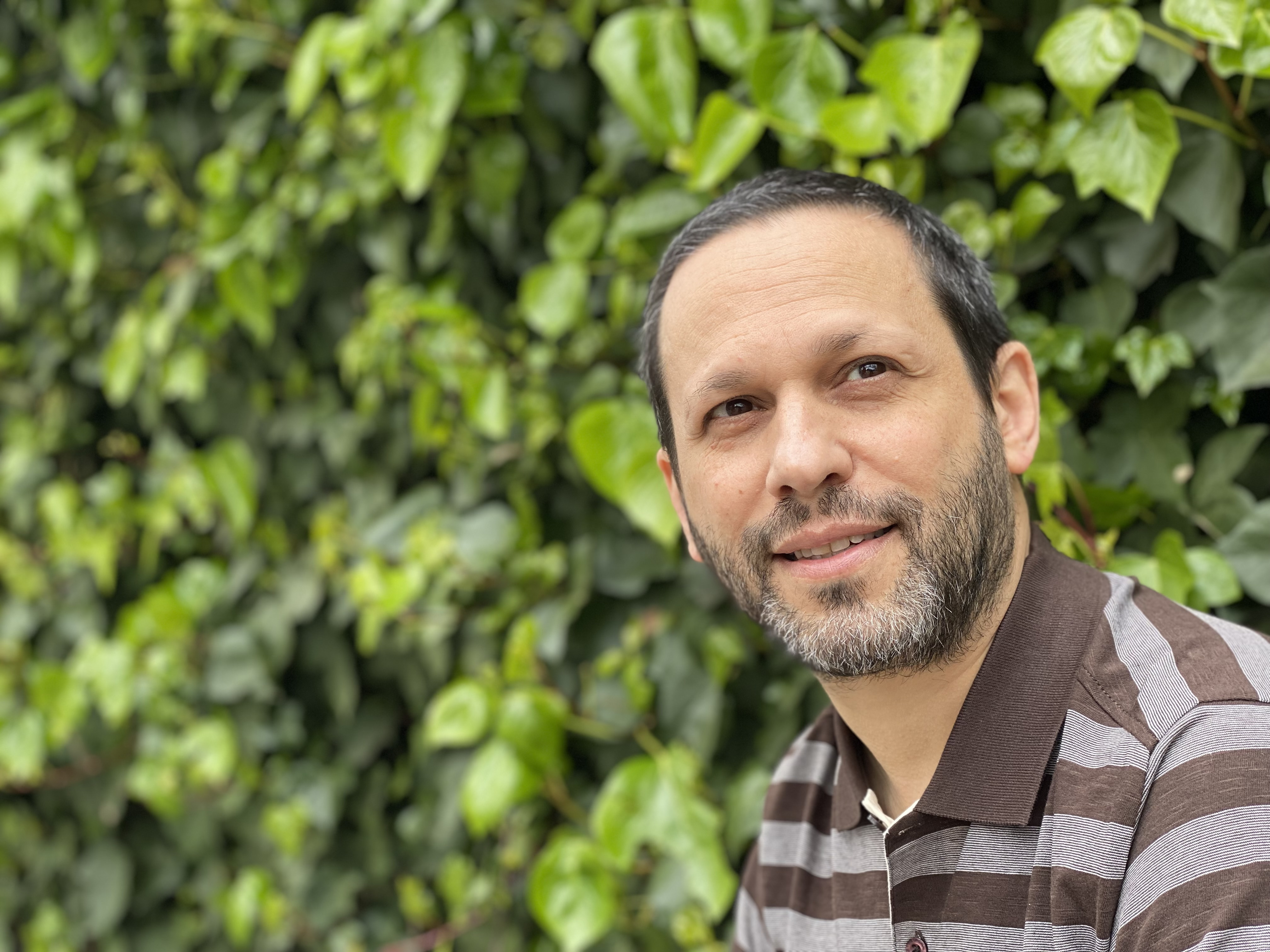 Photo of translator Lawrence Schimel against a green trees.