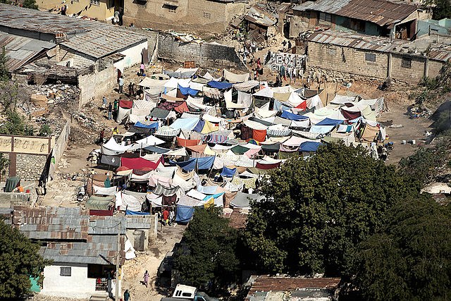 Image of makeshift tents within a neighorhood with houses affected by the earthquake.